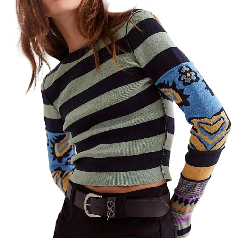 Person wearing a striped sweater with colorful sleeves on a plain background